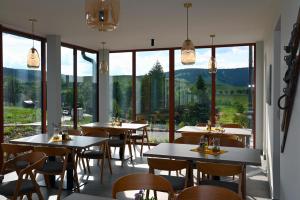 a restaurant with tables and chairs and large windows at Penzion Königův mlýn in Loučná pod Klínovcem