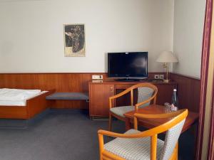 Habitación de hotel con cama, TV y silla en INVITE Hotel Löwen Freiburg, en Freiburg im Breisgau