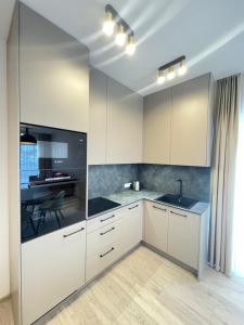 an empty kitchen with white cabinets and a table at Mano jura 2-Apartments in Palanga