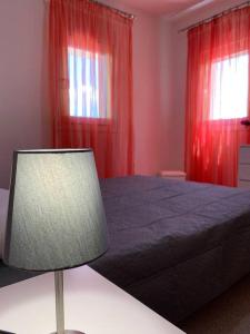 a bedroom with a bed with red curtains and a lamp at Cute seaside apartment in Kalloni