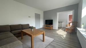 ein Wohnzimmer mit einem Sofa und einem Tisch in der Unterkunft Fischers Nordseehaus Bungalow mit Garten in Wilhelmshaven