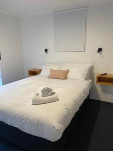 Una cama blanca con una toalla encima. en Archipelago Apartments Esperance en Esperance