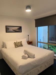 a bedroom with a large white bed with a window at Archipelago Apartments Esperance in Esperance