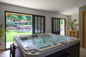 uma grande banheira num quarto com um pátio em Domaine du Bugassou, Chambres, Table d'hôtes & SPA em Belvès