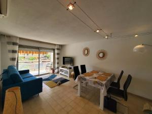 een woonkamer met een tafel en een blauwe bank bij MIOUGRANO 2 Pieces Climatise 47m2 Piscine, Parking in Fréjus