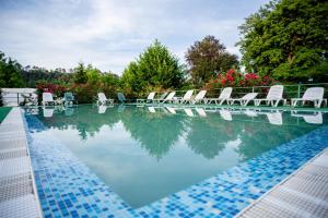 a swimming pool with white chairs and a pool of water at HOTEL MARION POIANA in Dumbrăveni