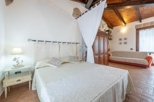 ein Schlafzimmer mit einem weißen Bett und einem Sofa in der Unterkunft Dependance Dei Ginepri in SantʼAntìoco