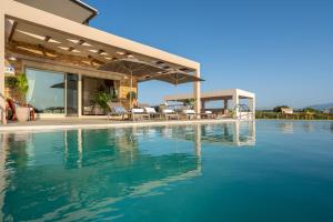 uma casa com uma piscina com cadeiras e um guarda-sol em Villa Anastasia - Luxury Living em Chania