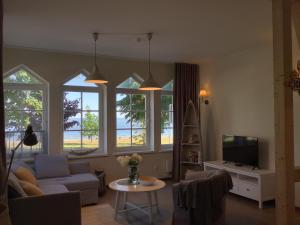 a living room with a couch and a tv and some windows at Vila MAY in Juodkrantė