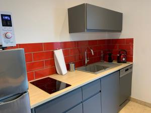 a kitchen with a sink and red tiles on the wall at Appartement avec Terrasse et piscine in Gréoux-les-Bains