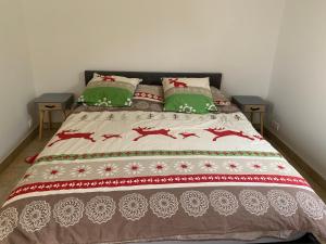 a bed with a red and white blanket and green pillows at Appartement avec Terrasse et piscine in Gréoux-les-Bains +6 photos