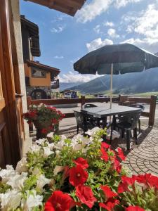 een patio met een tafel, bloemen en een parasol bij Snowflake Apartment in Livigno