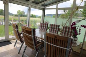 uma sala de jantar com mesa, cadeiras e janelas em Pension Agathe em Beilngries