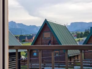 a log cabin with a green roof with mountains in the background at Apartmani Gala Žabljak in Žabljak