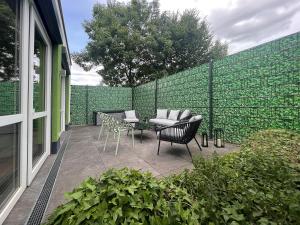 a patio with chairs and a table in front of a green wall at Eco Smart Apartments Nürnberg Süd in Nürnberg