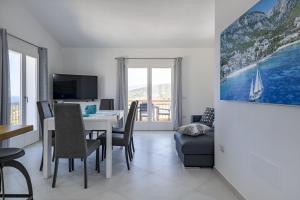 una sala da pranzo con tavolo, sedie e TV di Appartamento vista Golfo a Cala Gonone