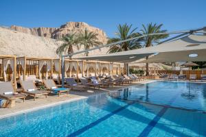 a pool at a resort with chairs and umbrellas at Oasis Spa Club Dead Sea Hotel - 18 Plus in Ein Bokek