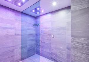 a bathroom with a glass shower with purple lighting at Alex Alpine Resort - Spa & Sports in Zermatt