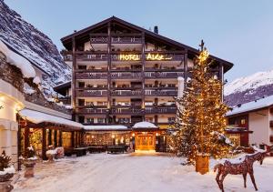 un hôtel avec un arbre de Noël devant lui dans l'établissement Resort Hotel Alex Zermatt, à Zermatt