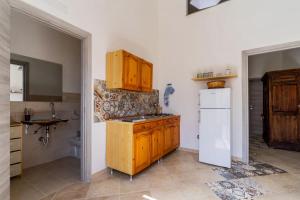 eine Küche mit Holzschränken und einem weißen Kühlschrank in der Unterkunft Casa Vacanza Lu Sule in Uggiano la Chiesa