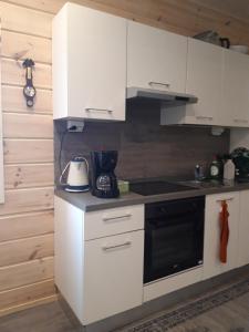 a kitchen with white cabinets and a black stove top oven at Suvantorinne in Sonkakoski