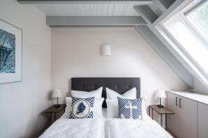 a white bedroom with a bed with blue and white pillows at Hagebutte- Domizil am Ostseewald in Zingst