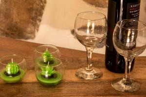 quatro copos de vinho com velas verdes numa mesa em Anemolia Tiny Stone House em Palekastron