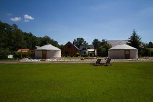 two benches in a field with two huts in the background at JURTLANDIA jurta LOFT in Lubiatowo