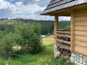 a building with a pile of logs next to a field at Domki na wzgórzu in Małe Ciche