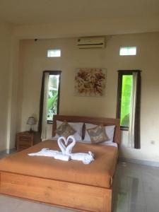 a bedroom with a bed with two white towels on it at Kenari House in Ubud