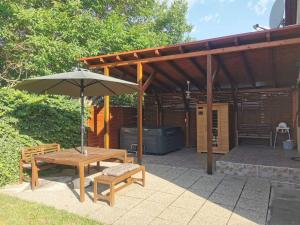 a patio with an umbrella and a table and bench at Garden Vendégház Velence in Velence