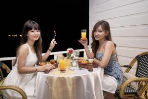 Morelo Water Villa في باتام سنتر: جلستا سيدتان على طاولة مع مشروبات