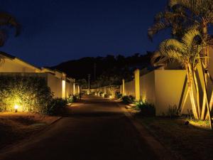 a street with a row of buildings and palm trees at night at Homm Stay Yumiha Okinawa by Banyan Tree Group in Onna