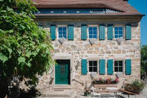 uma casa de pedra com persianas azuis e uma porta verde em Idyllischer Bauernhof mit viel Charme em Arnsdorf