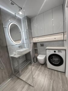 een badkamer met een wasmachine en een wastafel bij Apartament KINGA nad rzeką Iławką in Iława