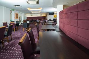 una sala da pranzo con tavoli, sedie e una parete rossa di Holiday Inn Express Bedford by IHG a Bedford