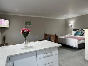 Luneburgh Cottages في شرق لندن: غرفة نوم مع سرير و مزهرية مع الزهور على منضدة
