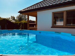 a large blue swimming pool in front of a house at Domki Zorza in Darłowo