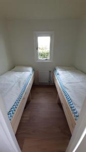two beds in a small room with a window at Huisje VOS in Schoonloo