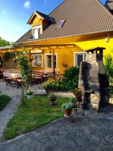 a yellow house with a stone fireplace in the yard at Appartementhaus 5. Jahreszeit in Hévíz