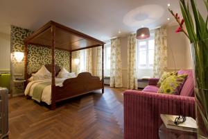 a bedroom with a canopy bed and a couch at Romantik Hotel Markusturm in Rothenburg ob der Tauber