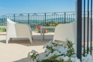 2 sillas blancas y una mesa en el balcón en Villa Sabrina 12, en Cagli