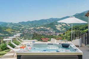 una bañera de hidromasaje en un patio con montañas al fondo en Villa Sabrina 12 en Cagli