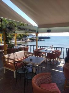 a restaurant with tables and chairs and a view of the water at Ammoudia Rooms in Agia Marina Aegina