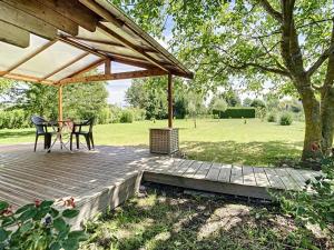une terrasse en bois avec une table et des chaises sous un pavillon dans l'établissement Le Châlet des Hortillonnages, à Amiens