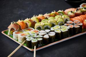 a platter of sushi and rolls on a table with chopsticks at The Rockefeller Hotel by NEWMARK in Cape Town