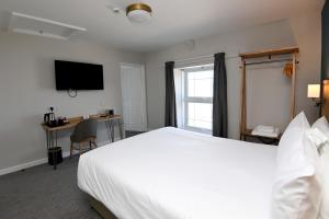 a hotel room with a bed and a desk and a television at Ship Inn in Aberporth