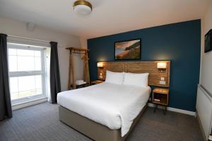 a bedroom with a large white bed and a blue wall at Ship Inn in Aberporth