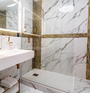 - une salle de bains blanche avec des murs en marbre et un lavabo dans l'établissement Magnifique loft / spa en face de la cathédrale !, à Narbonne