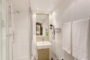 a white bathroom with a sink and a shower at MEININGER Hotel Wien Downtown Franz in Vienna